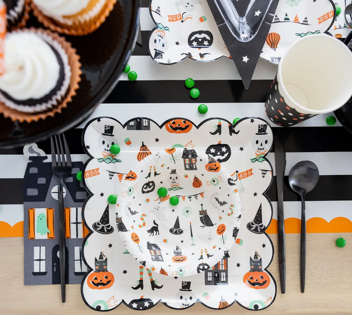 Halloween-themed table setting with decorative plates, cups, and utensils.
