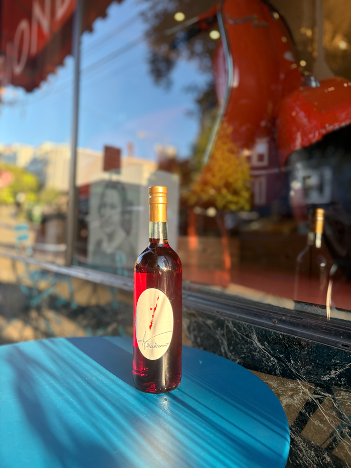Red Americano liquor bottle with gold cap on blue tabletop