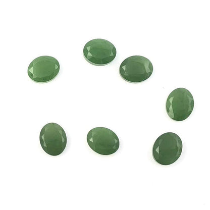Seven green A Grade 8x10mm faceted cabochons arranged on white background