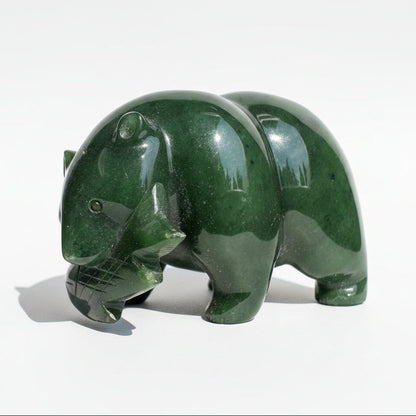 A polished dark green jade sculpture of a bear standing on a white background.