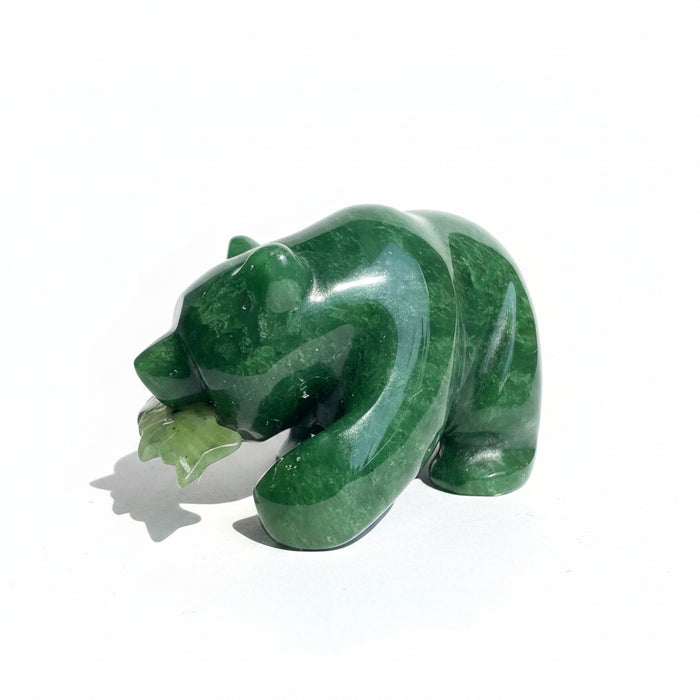 A dark green jade bear with a fish in its mouth on a white background