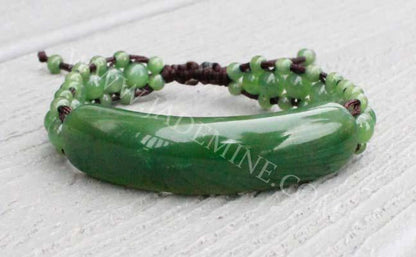 Bracelet 1833-12 with glossy curved green centerpiece and small round beads on dark cord