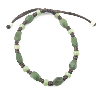 Bracelet with green stone chips and pale green beads on a dark braided cord.