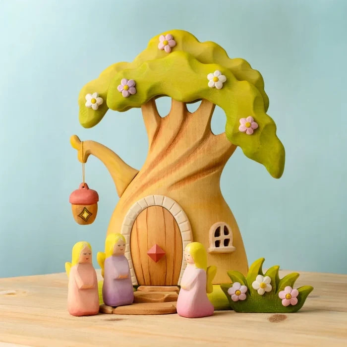 Wooden toy treehouse with three small figures on a wooden surface and light blue background