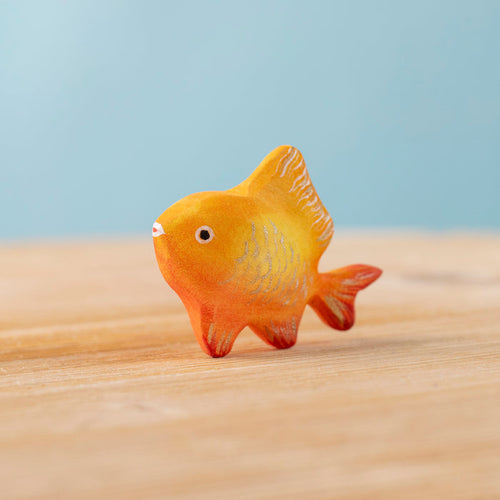 Toy fish on a sandy surface with a blue background