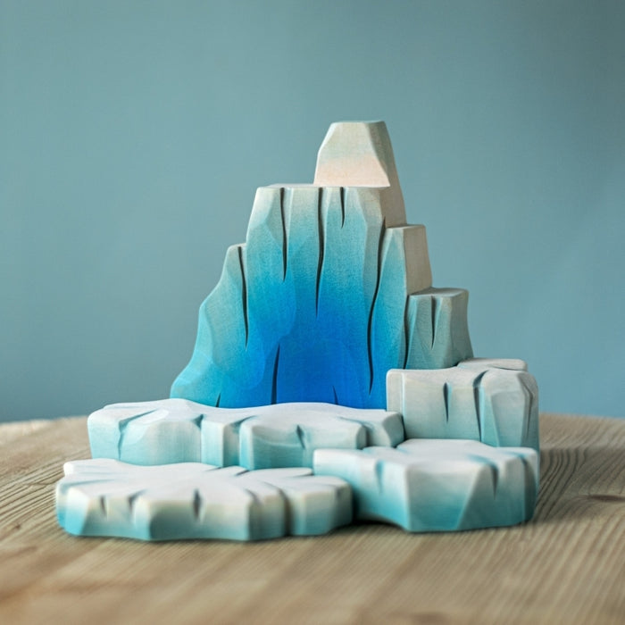 Iceberg sculpture with gradient blue and white colors on a wooden surface and light blue background