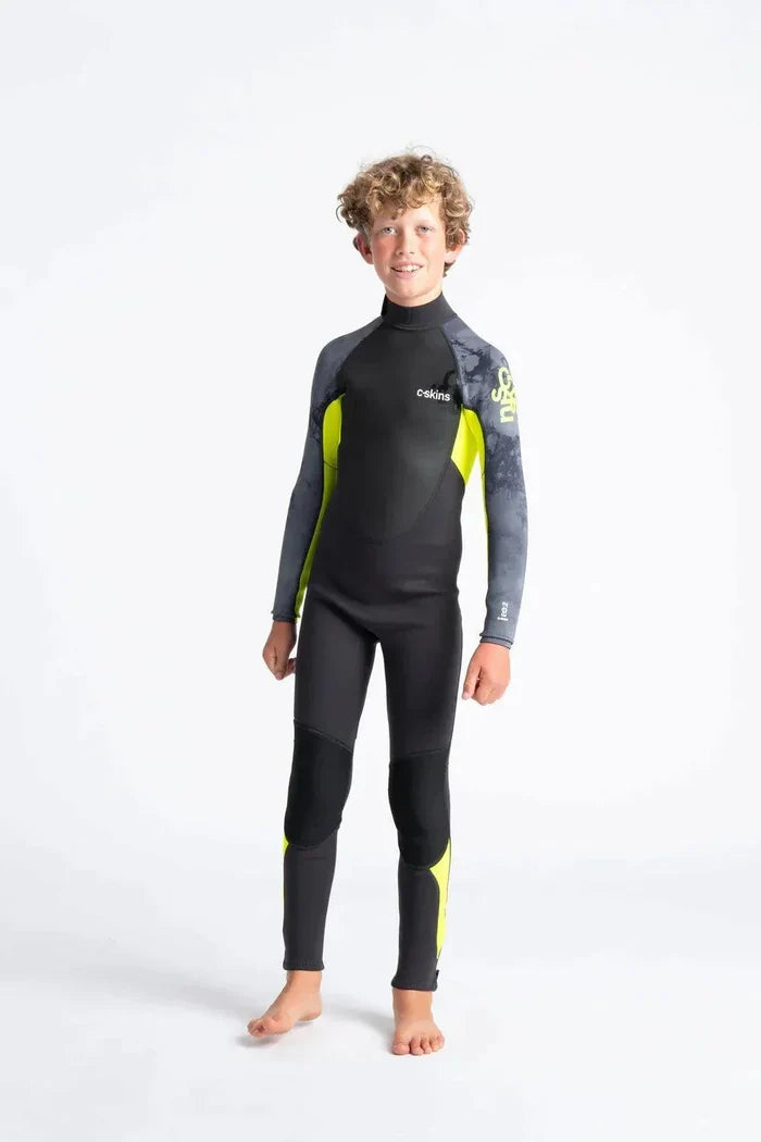 Boy wearing C-Skins Element 3/2 Junior wetsuit in black with yellow and grey accents