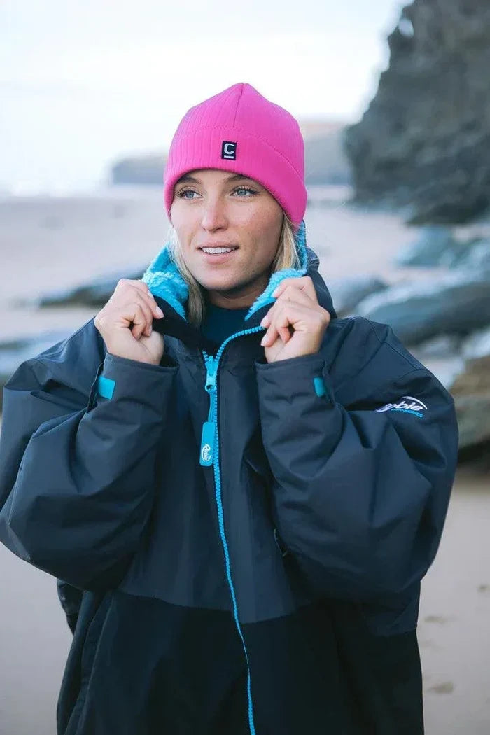 Woman wearing C-Skins Storm Chaser 2mm neoprene beanie pink on beach