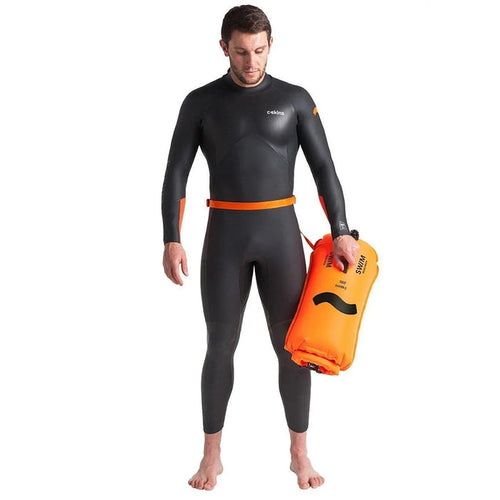 Man in wetsuit holding C-Skins Swim Buoy 28L Dry Bag Safety Orange for open water swimming