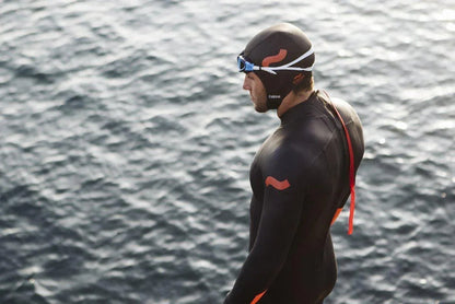 C-Skins Swim Research Cap worn by swimmer in wetsuit beside water, open water swim gear