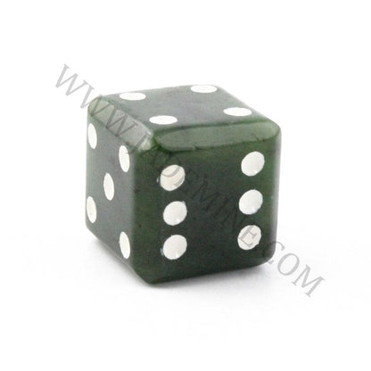 Close up of a single dark green jade die showing white pips