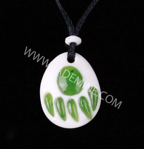 White bone pendant with green jade bear paw inlay on a black cord.