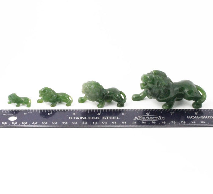 Series of green stone lion figurines in increasing sizes with a ruler for scale