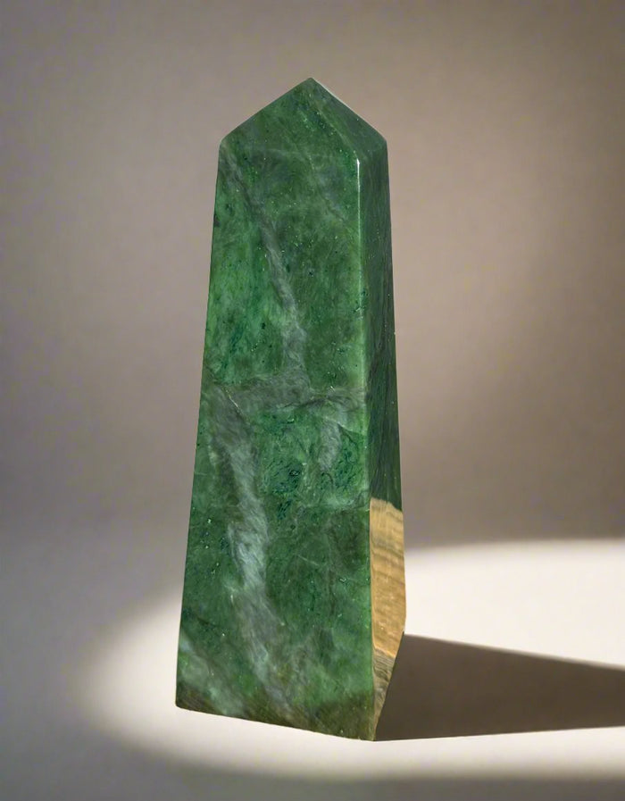 Polished Canadian Jade Obelisk standing upright with a pointed tip against a neutral backdrop.