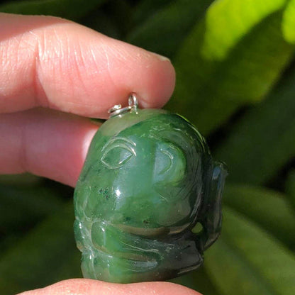 Hand held green jade cartoon monkey charm with carved face and loop at top.
