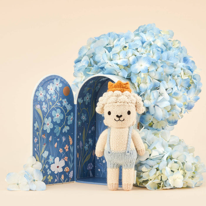 Knitted bear toy with a blue floral book and hydrangeas on a beige background