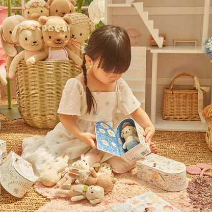 Child playing with teddy bears and a book in a cozy indoor setting