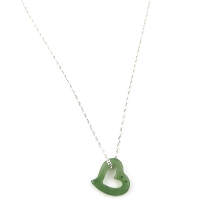 Green jade heart pendant with a hollow center on a silver chain against a white background