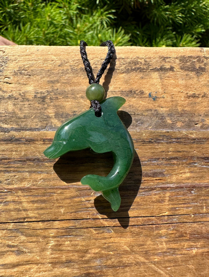 Green jade dolphin pendant on a black braided cord.