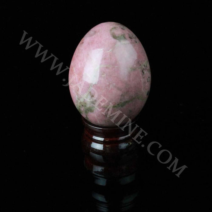 Pink rhodonite egg on a dark wooden stand
