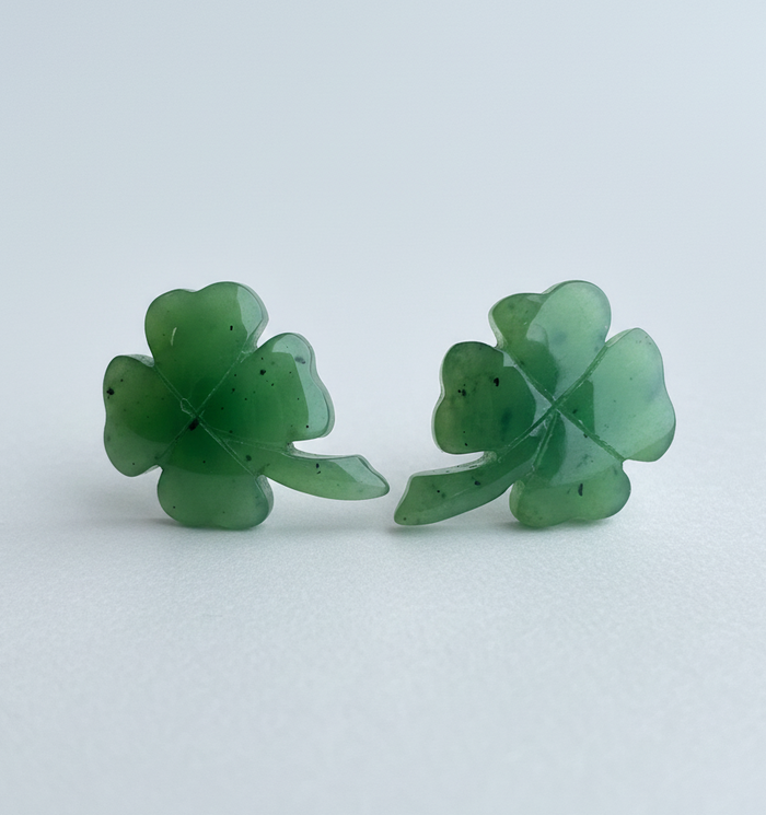 Pair of green four-leaf clover earrings on a light gray background