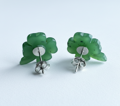 Pair of green clover-shaped earrings on a light blue background