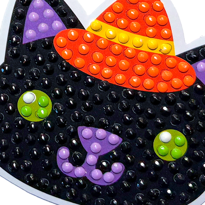 Halloween-themed decorative item with black cat face, orange candy corn hat, and colorful buttons.