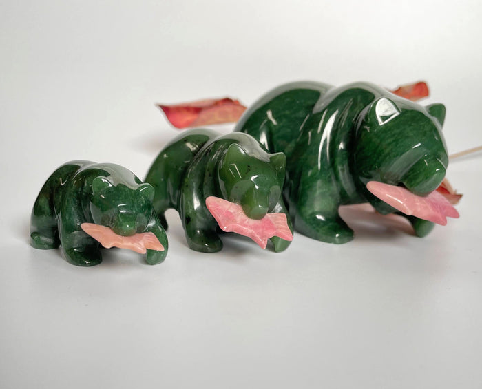 Three green jade bear figures with pink rhodonite fish on a white background