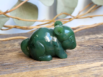 Green jade chinchilla figurine handcrafted and polished on a rustic wooden surface.