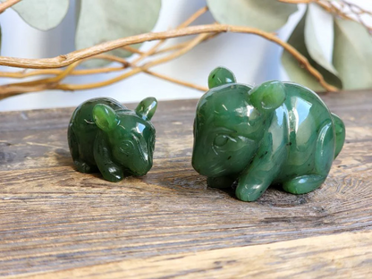 Two jade chinchilla figurines in dark green on a wooden surface