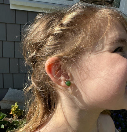 Green jade heart stud earring worn on a woman's ear outdoors