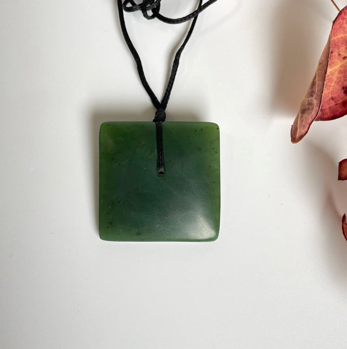 Satin finish square jade pendant in deep green with top hole on black cord