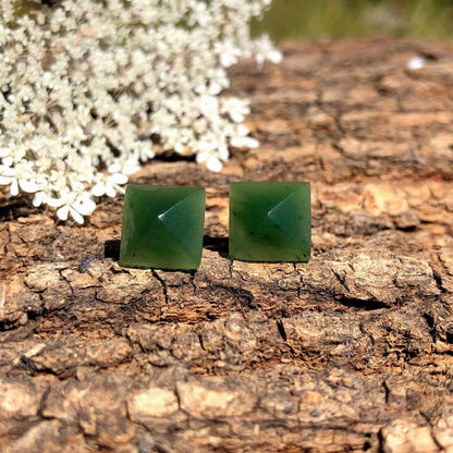 Pair of green jade square pyramid earrings 15mm with posts on rugged tree bark background.