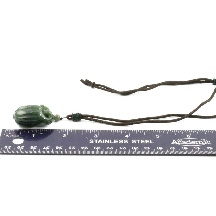 Green jade squash pendant carved with leaf pattern on brown cord necklace.