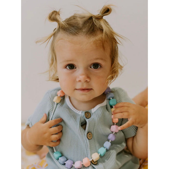 Child holding a colorful necklace with a plain background