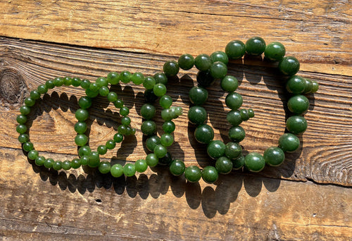 Green mala bead bracelets arranged on a rustic wooden surface.