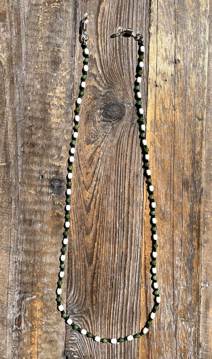 Jade and bone beaded mask or eyeglass holder with white bone beads and green jade beads on a rustic wooden surface.