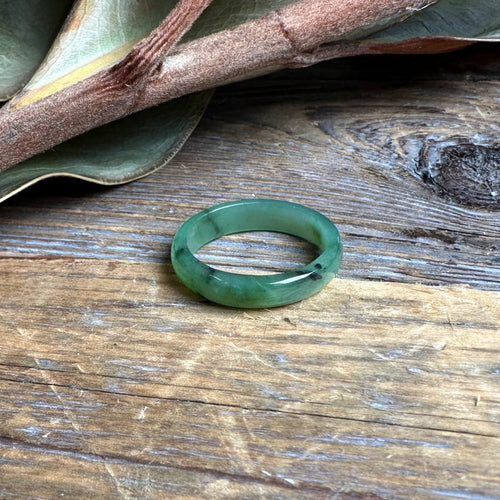 Narrow jade band ring 5mm resting on a rustic wooden surface