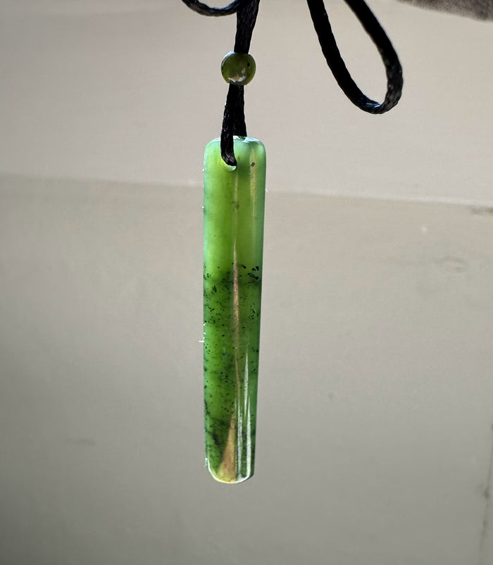 Lime green jade drop pendant on a black cord with a small round bead