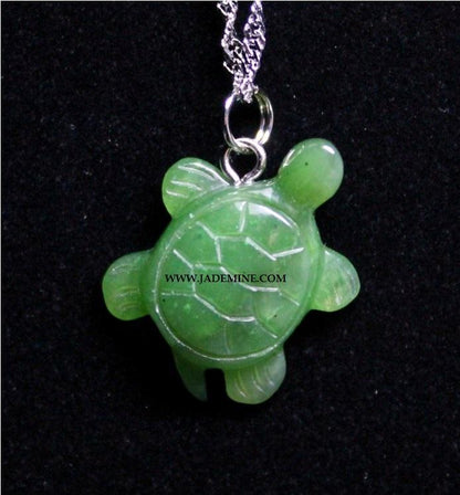 Close up of green turtle pendant on a silver chain against a black background