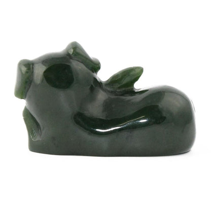 Dark green glossy pig figurine seen in a side view in a reclining pose