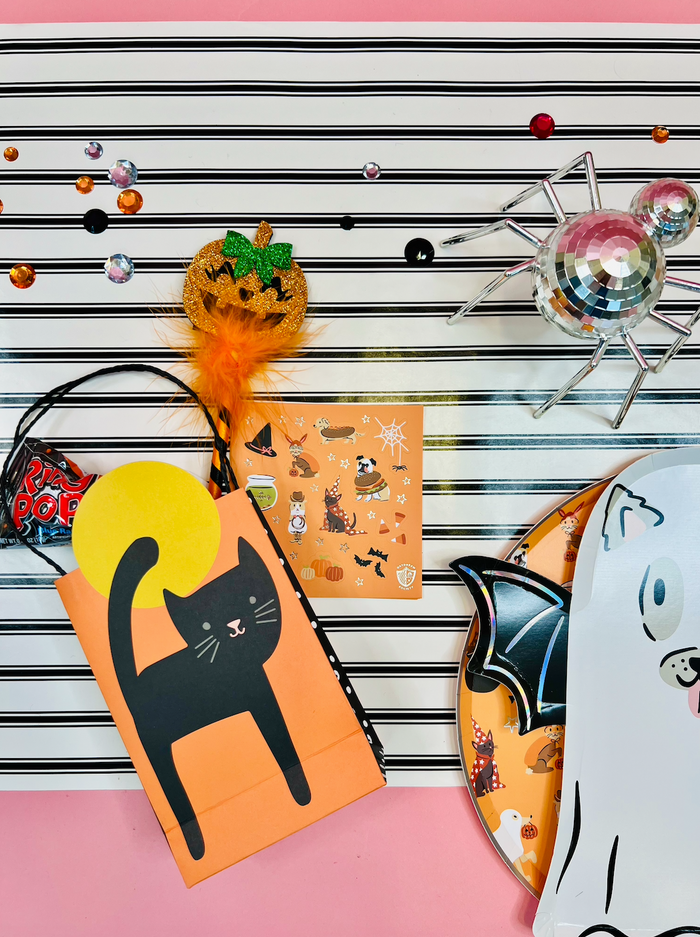 Halloween-themed items including a black cat card, orange envelope with black cat design, and decorative elements on a striped background.