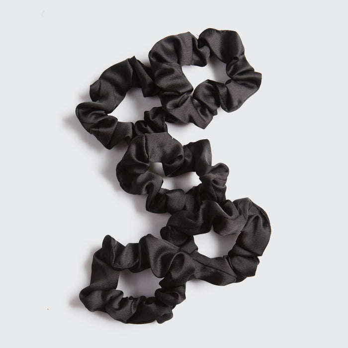 Set of black scrunchies on a light gray background