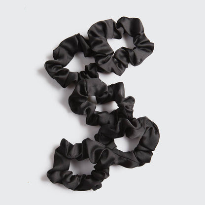 Set of black scrunchies on a light gray background