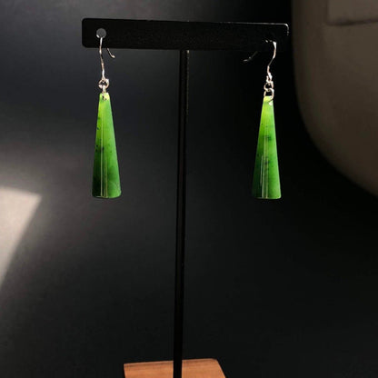 Green jade cone earrings with silver hooks displayed on a black stand