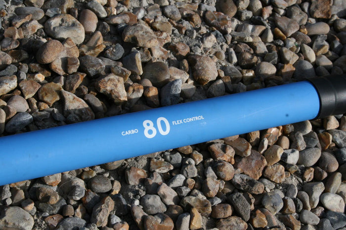STX Carbon 80% 3-piece SUP paddle shaft with flex control, blue, on rocky ground