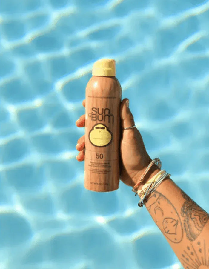 Sun Bum Original SPF 50 Sunscreen Spray held by hand above pool water