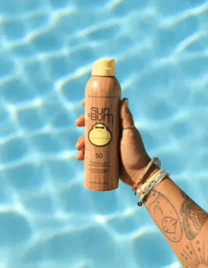 Sun Bum Original SPF 50 Sunscreen Spray held by hand above pool water